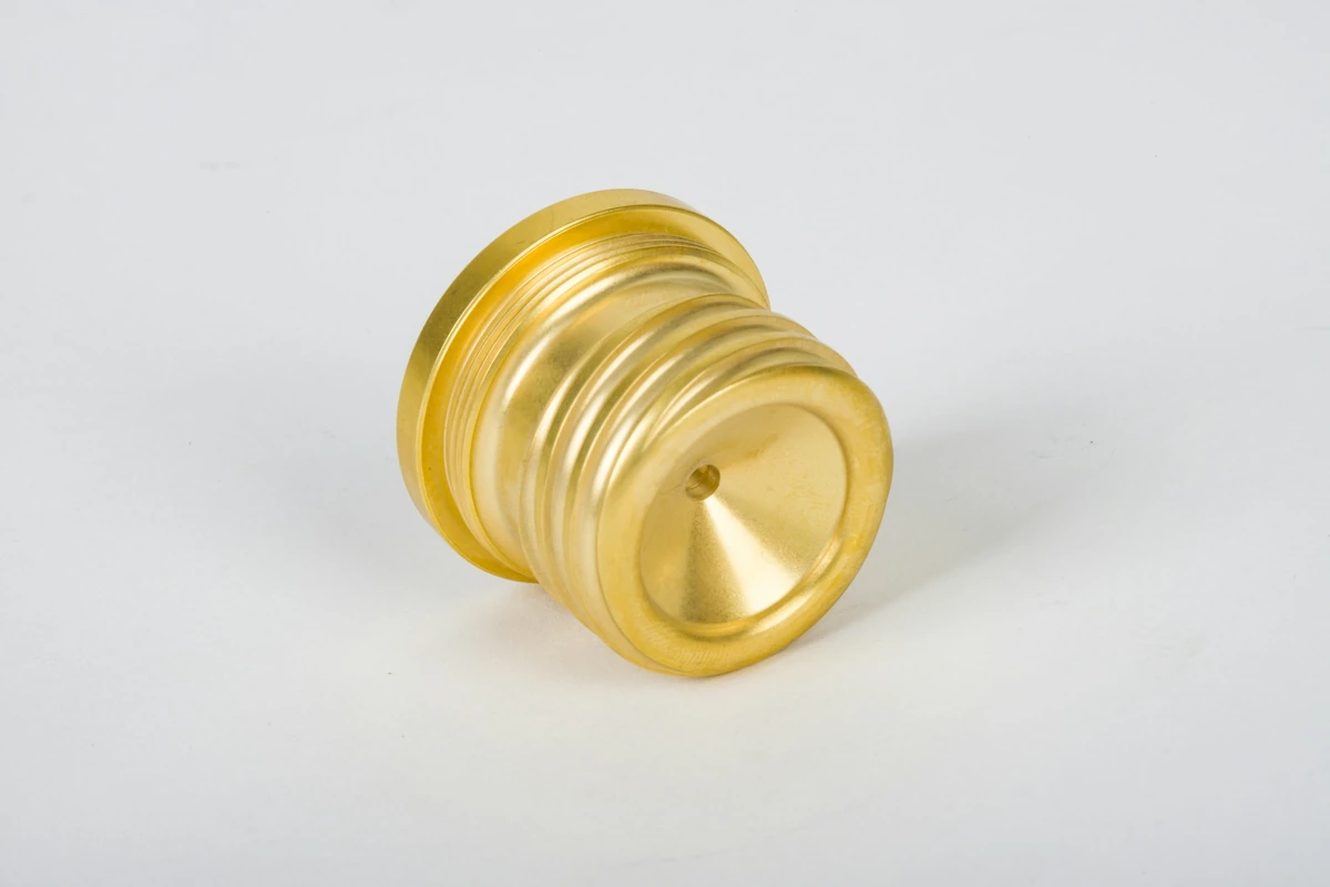 Gold-colored turned component with stepped surfaces